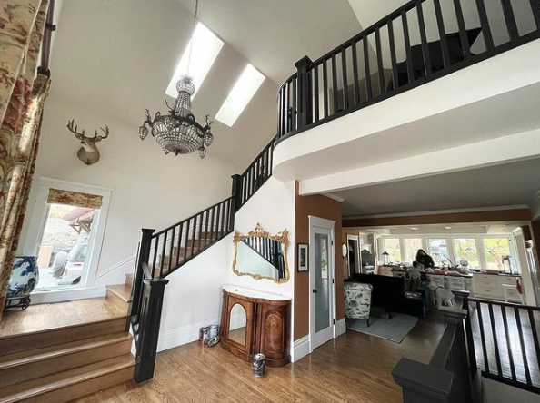 interior residential painting in Kelowna. view of stairwell. walls are white, railing is black. A chandelier hangs above the stairs