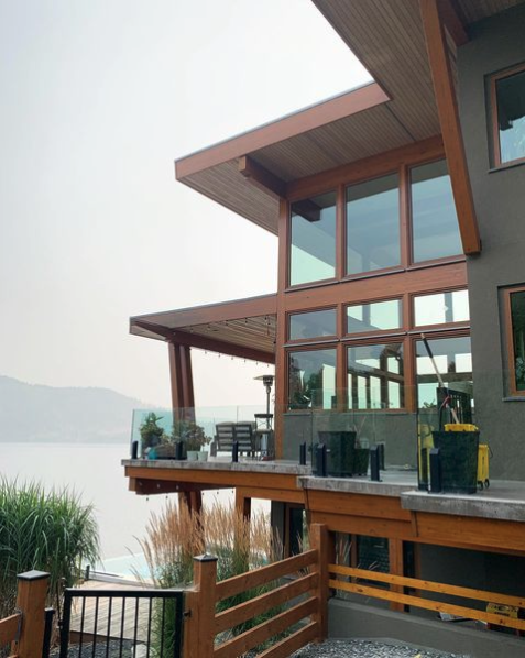 large house with lots of windows overlooks the Okanagan lake. Wood trim is freshly stained
