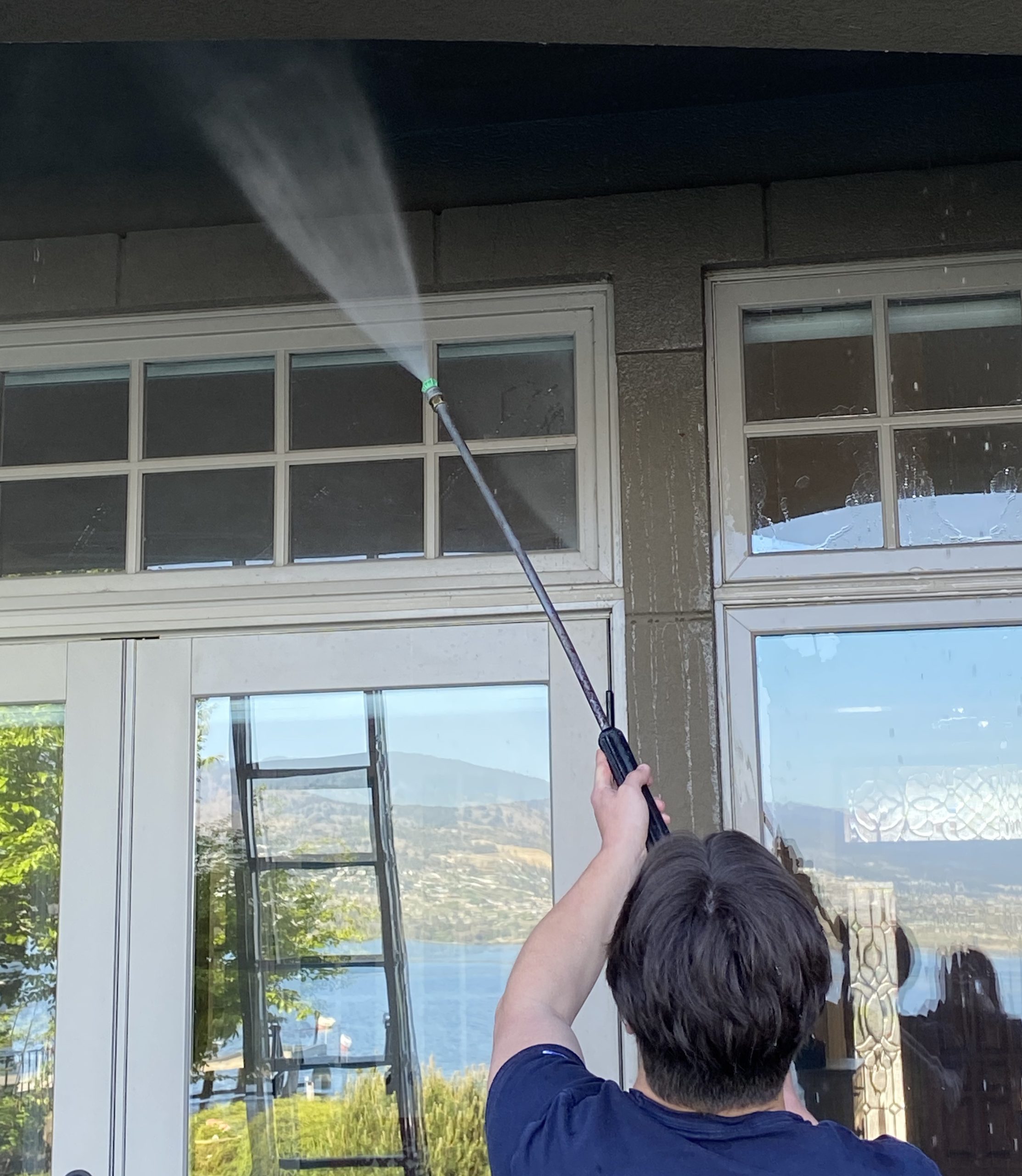 WORKER PRESSURE WASHING AN EXTERIOR RESIDENTIAL HOME