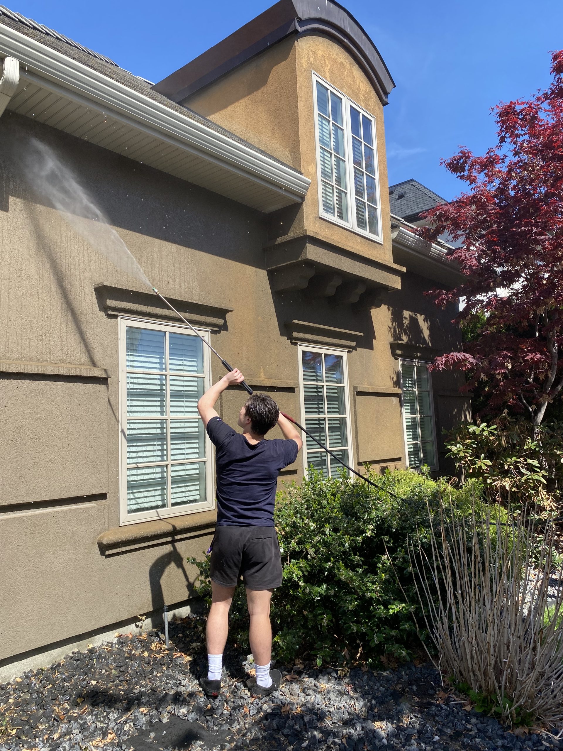 professional soft washer working on a home's exterior in kelowna bc